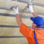 Technician installing insulation in a home, emphasizing HVAC efficiency and maintenance for improved heating and cooling performance.