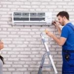Technician performing maintenance on air conditioning unit while homeowner observes, highlighting HVAC service and repair expertise.