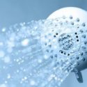 Showerhead with water droplets against soft blue tones, emphasizing cleanliness in plumbing services by Carmine's.