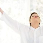 Person in white shirt with arms raised, expressing a sense of relief or joy, symbolizing the benefits of clean air and health in relation to HVAC services.