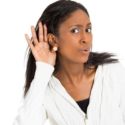 Woman in light hoodie listening attentively about plumbing, heating, and air conditioning services from Carmine's Plumbing.