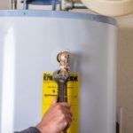 Hand adjusting valve on a water heater, emphasizing maintenance for efficient plumbing and heating services in Danbury, CT.