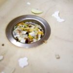 Garbage disposal with food scraps and debris around the drain, highlighting potential issues needing repair or maintenance.