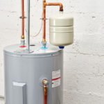 Water heater with copper pipes and pressure relief valve, illustrating maintenance concerns and potential leaks discussed by Carmine's Plumbing, Heating & Air Conditioning.