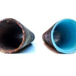 Two pipes: a rusty metal pipe and a clean plastic pipe, illustrating plumbing maintenance and corrosion prevention.