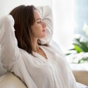 Woman relaxing on a couch in a serene indoor setting, highlighting plumbing and HVAC service awareness for homeowners.