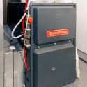 Goodman furnace with grey metallic casing and red logo, showcasing HVAC connections for home heating efficiency.