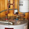 Water heater with copper piping, insulation, and pressure relief valve, by Carmine's plumbing services.