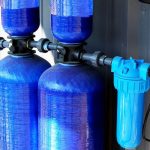 Water filtration system components, featuring two large blue tanks and a blue filter, emphasizing home water safety and quality.