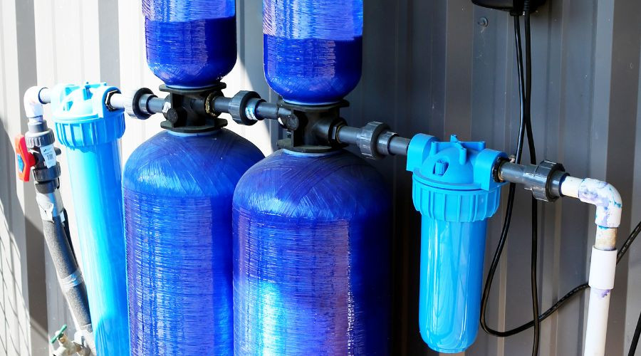 Water filtration system components, featuring blue tanks and plumbing, by Carmine's Plumbing.