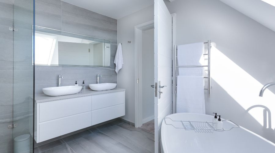 Modern bathroom design featuring dual sinks, natural light, and sleek cabinetry by Carmine's Plumbing.