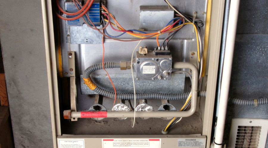 Detailed interior of a heating system with wires, gas valve, and control components from Carmine's HVAC solutions in Danbury.